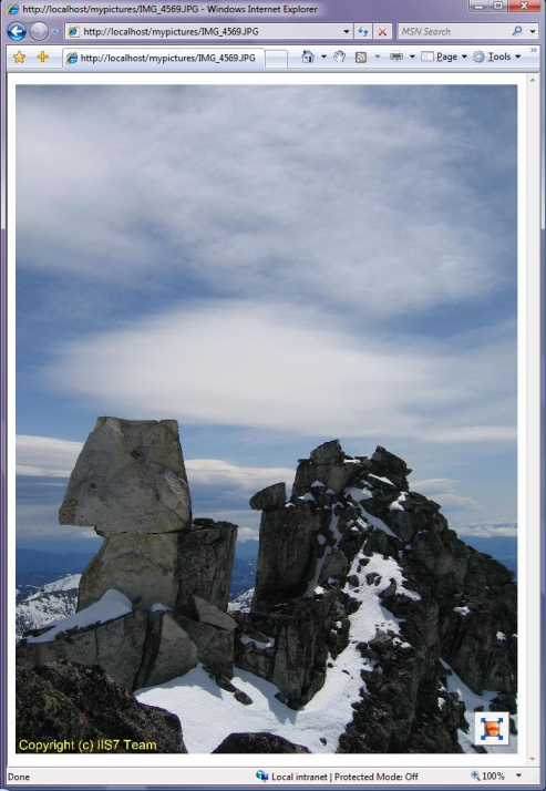 Screenshot della pagina Web che mostra un'immagine di montagne rocciose ricoperte di neve sullo sfondo di un cielo nuvoloso.